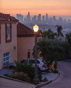 a street light on the side of a road near some buildings and palm trees in front of a cityscape