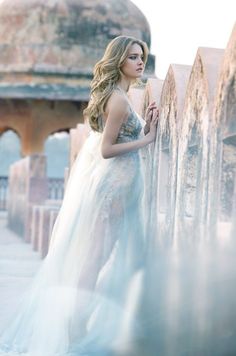 a woman in a white dress leaning against a wall