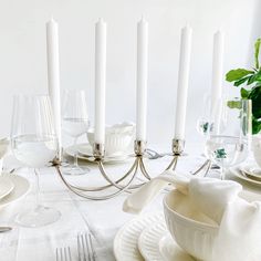 a white table setting with candles and dishes