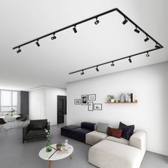 a modern living room with white walls and gray flooring is furnished with black and white furniture