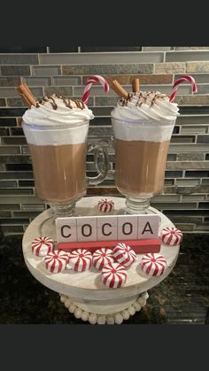 two glasses filled with hot chocolate and candy canes sitting on top of a table