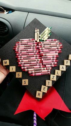 a graduation cap decorated with crayons and scrabbles in the shape of a heart