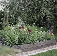 a large wooden planter filled with lots of flowers next to a lush green field