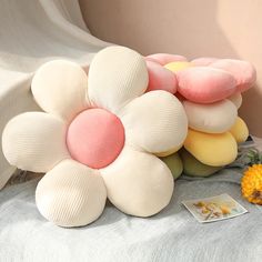 a bunch of pillows sitting on top of a bed next to a flower shaped pillow