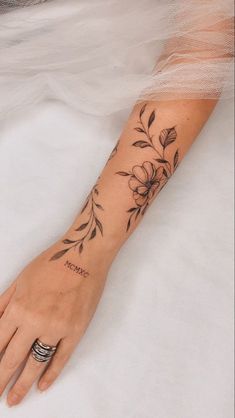 a woman's arm with flowers on it and a wedding ring in the middle