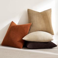 four pillows stacked on top of each other in front of a white wall and floor