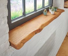 a window sill with two potted plants sitting on it's ledge next to a window