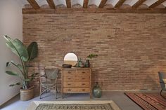 a living room with a brick wall and rugs on the floor in front of it