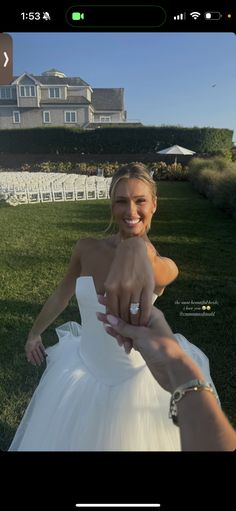 a woman in a wedding dress pointing her finger at the camera with a house in the background