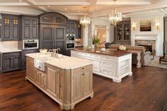 a large kitchen with wooden floors and gray cabinets, white counter tops, and an island in the middle