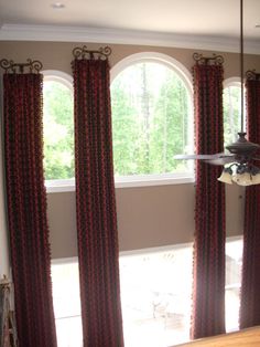 a living room with two large windows and red drapes on the window sill