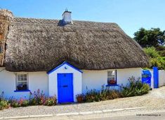 a thatched roof house with blue doors and windows