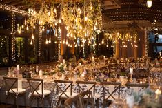 a banquet hall with tables and chairs covered in white tablecloths, chandeliers and lights hanging from the ceiling