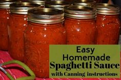 several jars filled with homemade spaghetti sauce on top of a red towel next to a pair of scissors