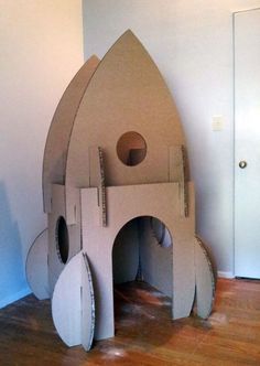 a cardboard rocket ship sitting on top of a hard wood floor