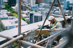 a construction worker working on the side of a tall building with lots of metal pipes