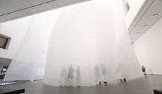 several people are standing in front of a white wall