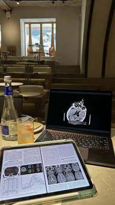 an open laptop computer sitting on top of a table next to a bottle of liquid