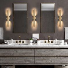 a bathroom with two sinks, mirrors and lights on the wall above them is shown