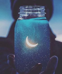 a person holding a jar with the moon in it