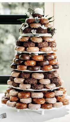 a tower of donuts sitting on top of a white table next to a window