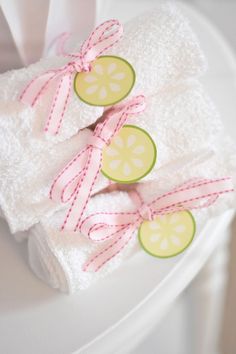 two white towels with pink bows and lemons on them are sitting on a plate