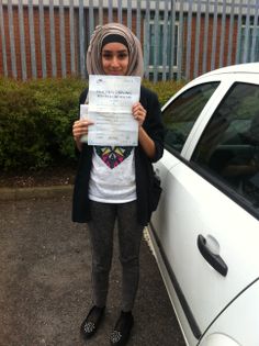 a woman standing next to a white car holding up a paper