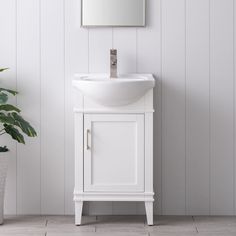 a white bathroom sink sitting under a mirror next to a potted plant on the floor