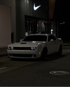 a white sports car parked in front of a building at night with the lights on