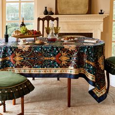 a dining room table covered with an elaborately designed tablecloth and matching green chairs