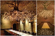 a long table is set with wine glasses and place settings under a chandelier