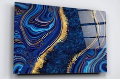 an abstract painting with blue, gold and white colors on the canvas is displayed in a room