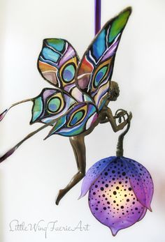 a stained glass ornament with a fairy holding a flower in it's hand