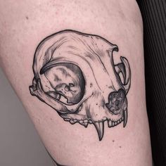 a black and white photo of a skull on the thigh, with an open mouth