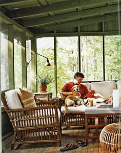 a person sitting on a porch with a dog and some chairs in front of them