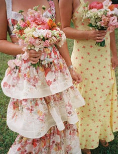 two women standing next to each other in dresses with flowers on the bottom tiers