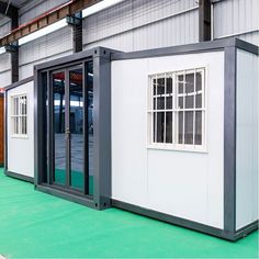 several portable buildings are lined up in a warehouse area with green flooring and white walls