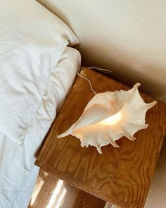 a wooden table with a white lamp on top of it next to a bed in a room