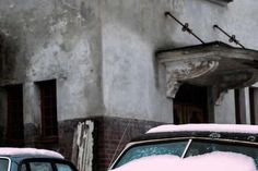 an old car covered in snow next to a building