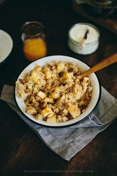 a bowl filled with food sitting on top of a wooden table next to two cups