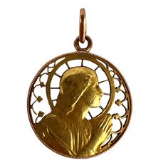 A French 18 karat (18K) yellow gold charm pendant designed as a round medal depicting the Virgin Mary within a pierced frame designed to resemble a halo and stained-glass window. The reverse engraved AMR with the date '24 Oct 47'. Stamped with the eagle's head for 18 karat gold and French manufacture, with an unknown maker's mark. Dimensions: 2.4 x 3.1 x 0.15 cm (not including jump ring) Weight: 3.62 grams (Chain not included) The Virgin Mary, Eagle Head, Maker's Mark, Pendant Design, Gold Charm, Virgin Mary, Glass Window, Makers Mark, Frame Design