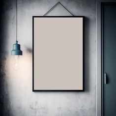 an empty frame hanging on the wall next to a light bulb and a lamp fixture