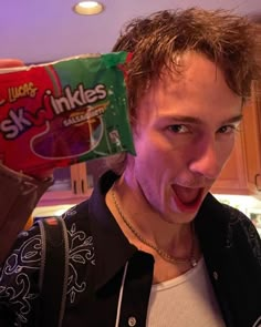 a young man holding up a box of skis in his hand and making a funny face