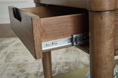 a close up of a drawer on a wooden table with a rug in the background