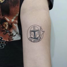 a tattoo on the arm of a person with a boba fett helmet in it