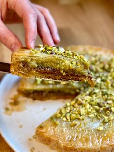 a person holding a piece of pie with pistachio toppings on it and another slice being lifted from the pie