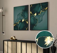 two paintings hanging on the wall next to a black vase with gold accents and a lamp