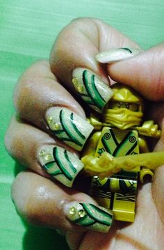 a hand holding a lego minifigure with green and white designs on it