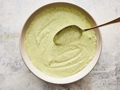 a white bowl filled with green sauce and a spoon