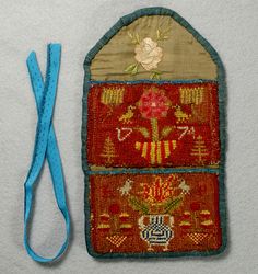 an embroidered purse with a blue strap and flower design on it, next to a pair of scissors